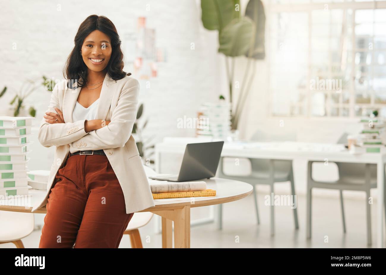 Donna d'affari afroamericana seduta sulla sua scrivania. Ritratto di una donna d'affari con le braccia incrociate. Giovane designer nella sua agenzia. Creativo Foto Stock