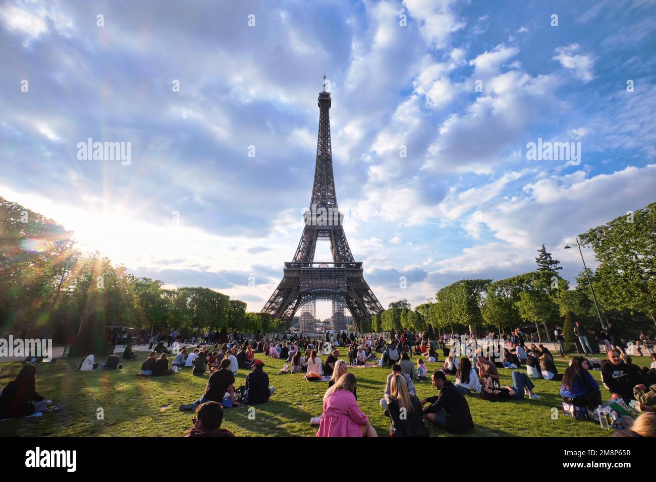 Parigi, Francia - Maggio, 2022: Persone in erba, avendo un picnic a Champ de Mars con la Torre Eiffel al tramonto Foto Stock