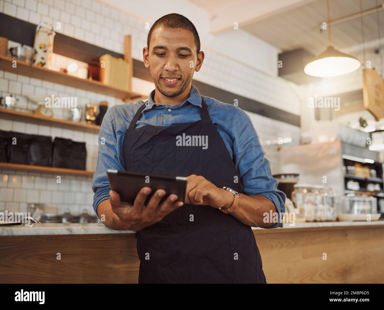 Barista che ordina le scorte per il suo coffee shop. Titolare di un'azienda che utilizza un tablet digitale nella sua cucina da caffè. Imprenditore di piccole e medie imprese che utilizza l'app online su Foto Stock