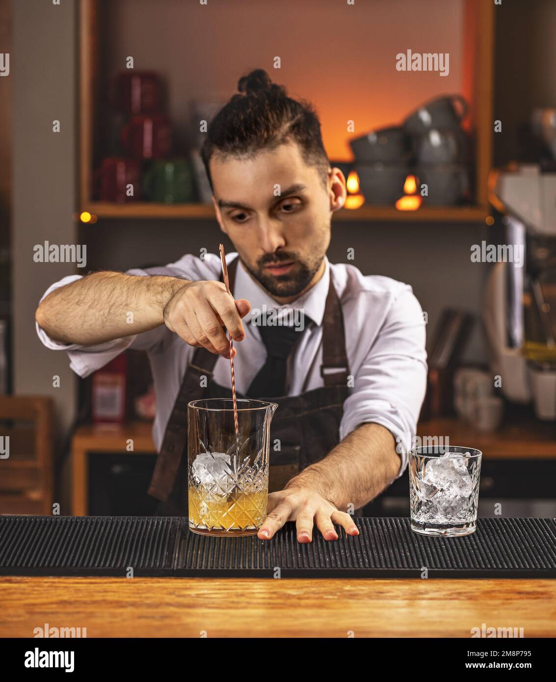 Giovane barman che mescola cocktail alcolico fresco con sciroppo di frutta dolce al banco del bar Foto Stock