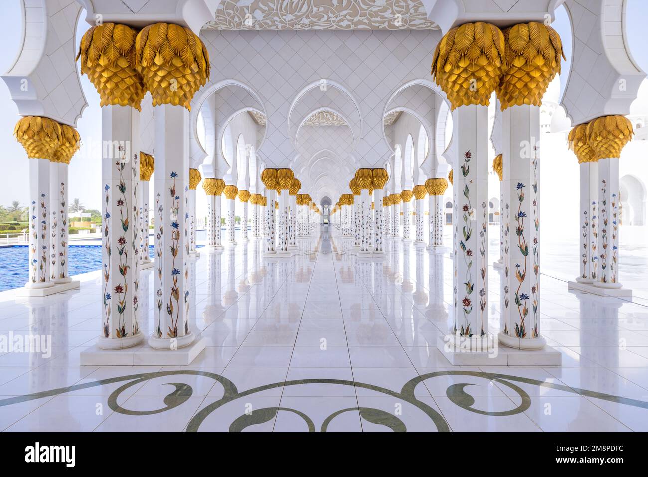 Vista simmetrica di un colonnato in marmo bianco alla moschea Sheik Zayed ad Abu Dhabi in piena luce del giorno Foto Stock