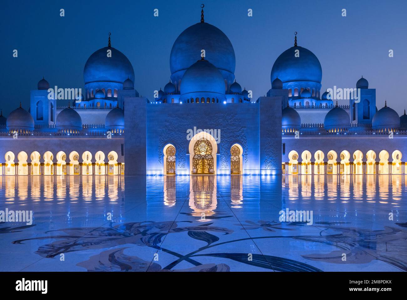 Vista ravvicinata simmetrica durante l'ora blu della maestosa moschea dello sceicco Zayed ad Abu Dhabi Foto Stock