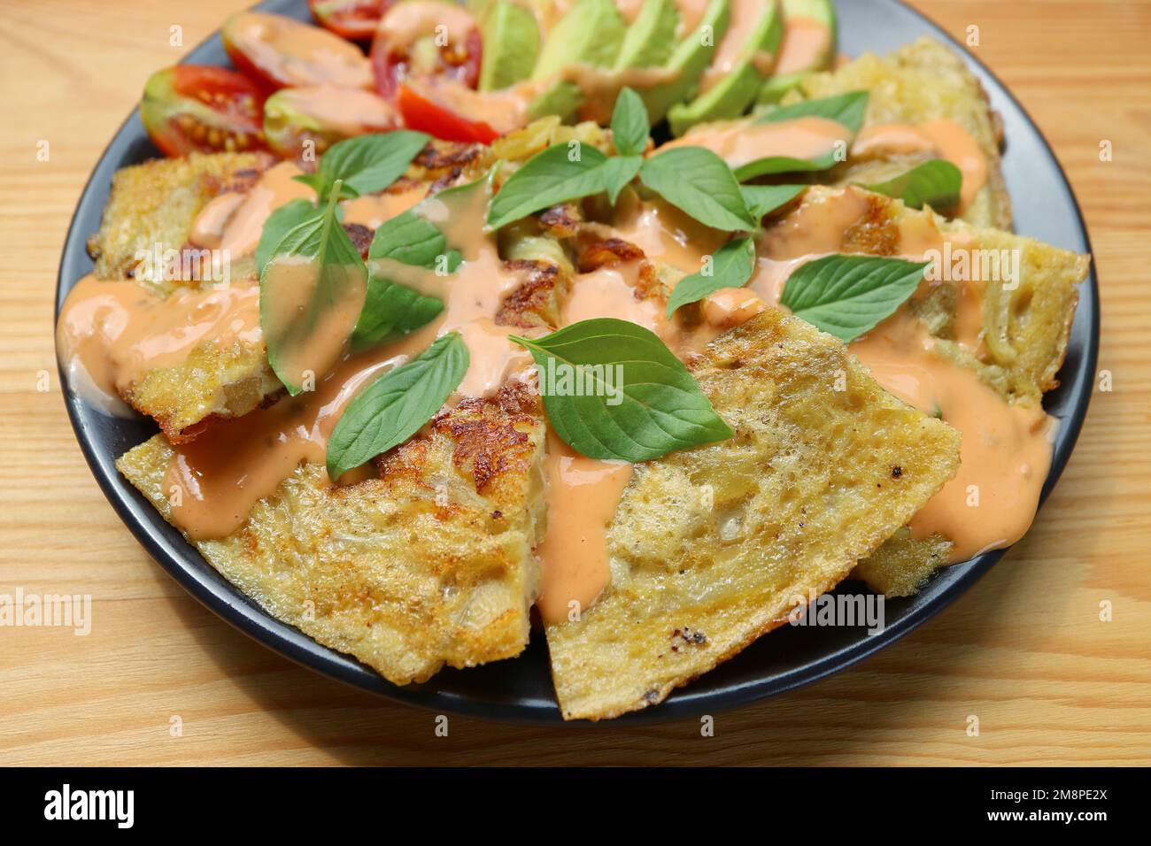 Deliziosa tortilla de Patatas o omelette spagnola guarnita con foglie aromatiche di basilico fresco Foto Stock