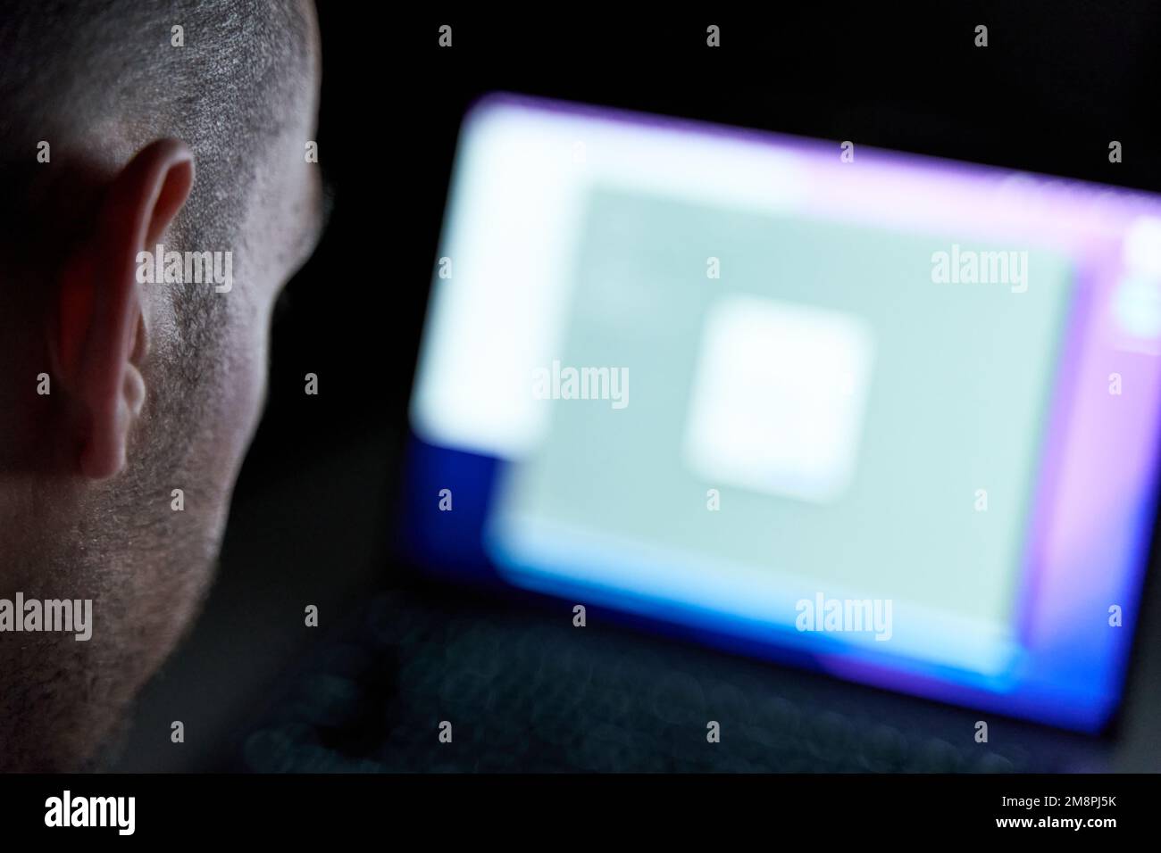 Concetto di hacking. Hacker maschio che guarda lo schermo del computer in una stanza buia Foto Stock