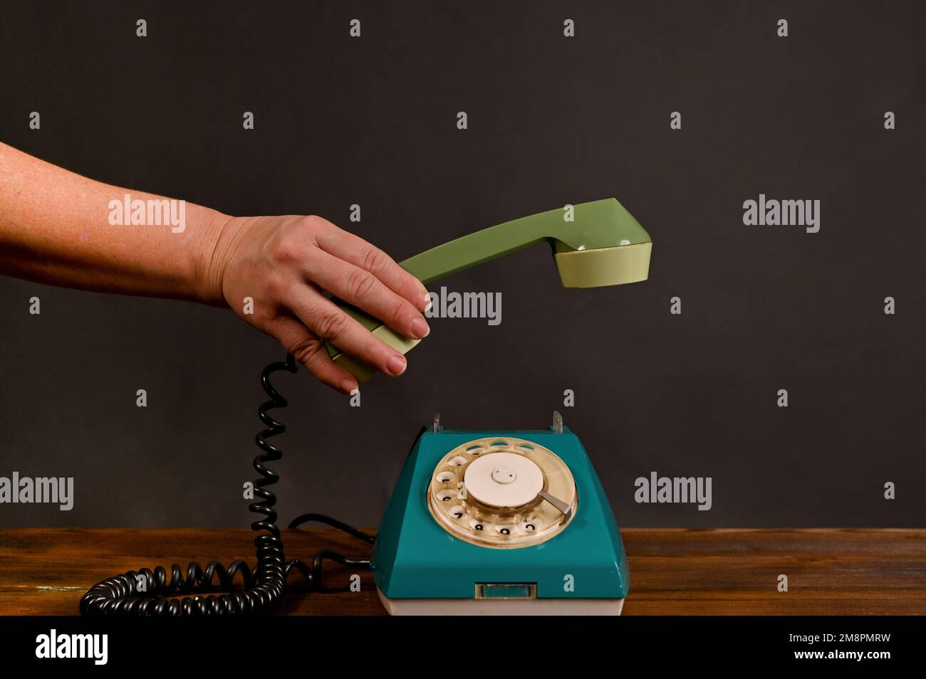 la mano di una donna mette giù il ricevitore di un vecchio telefono vintage. Foto Stock