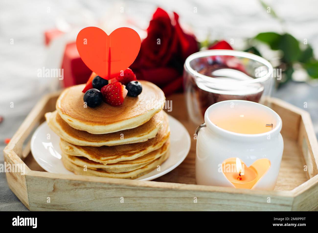 Colazione o brunch di San Valentino. Frittelle fatte in casa con bacche, tazza di tè e rose rosse Foto Stock