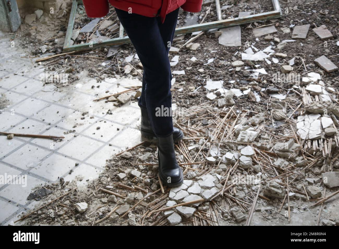 Una persona in un edificio distrutto in rovina dopo un attacco aereo. Crisi di guerra e disastro umanitario concetto. Foto Stock