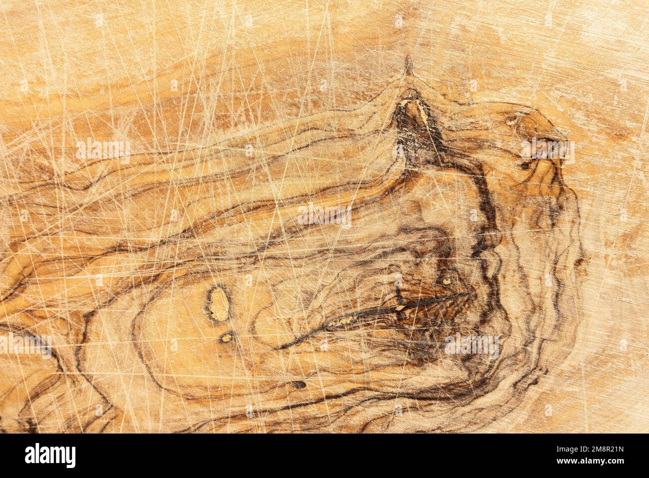 dettaglio primo piano di un tagliere di legno di ulivo usato con tagli, scanalature e patina d'uso Foto Stock