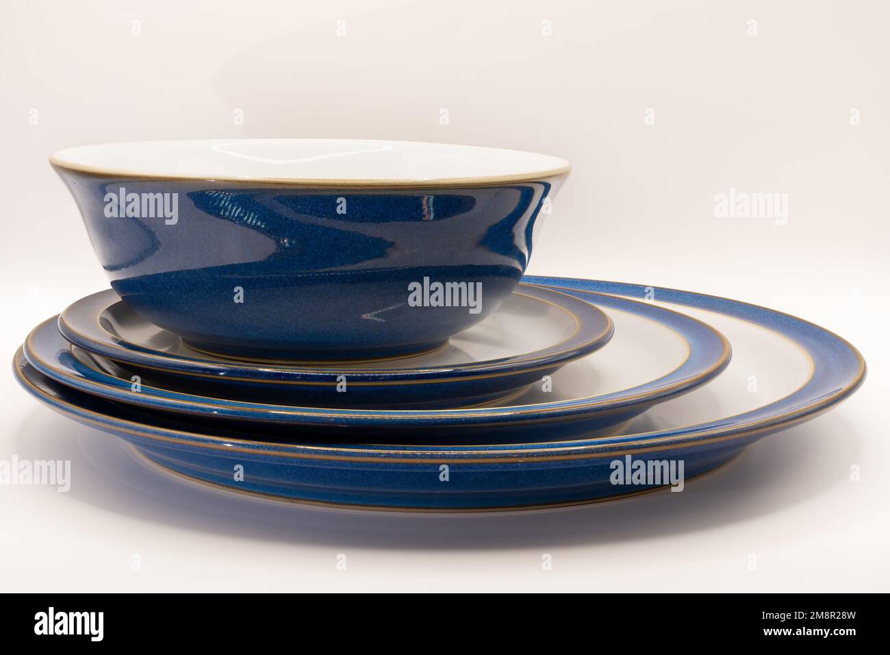 una ciotola blu e piatti di tre dimensioni in bianco con bordi blu e rifiniture dorate Foto Stock