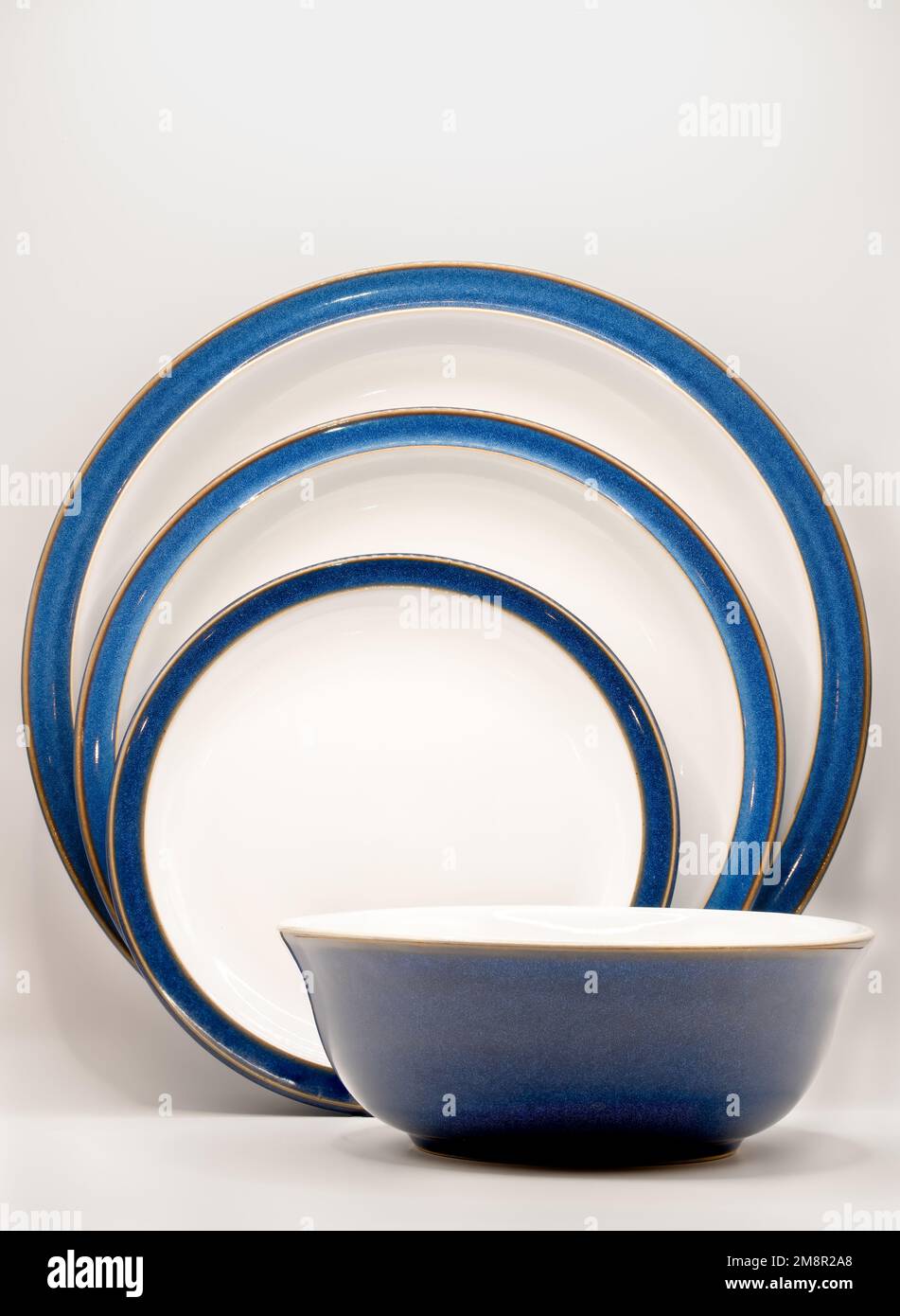 una ciotola blu e piatti di tre dimensioni in bianco con bordi blu e rifiniture dorate Foto Stock