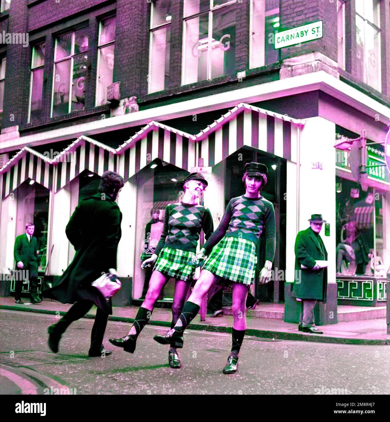 Un uomo e una donna che si posano in abiti identici di jumper e gonna nella elegante Carnaby Street, Londra 1968. Immagine di post-produzione colorata. Foto di Tony Henshaw Archivio Foto Stock