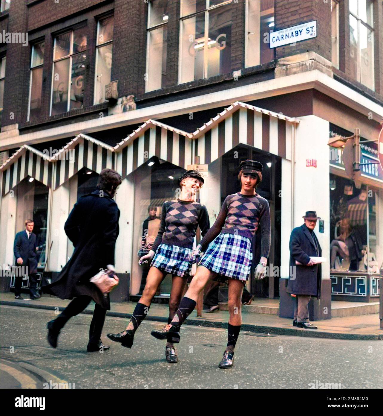 Un uomo e una donna che si posano in abiti identici di jumper e gonna nella elegante Carnaby Street, Londra 1968. Dopo la produzione colorato. Foto di Tony Henshaw Archivio Foto Stock