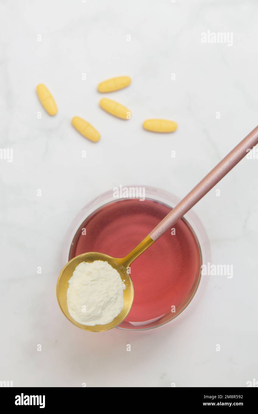 Additivi alimentari eccellenti. Polvere di proteina del collagene, pillole, cucchiaio e bicchiere d'acqua. Supplemento collagene per pelle, articolazioni e budella. Foto Stock