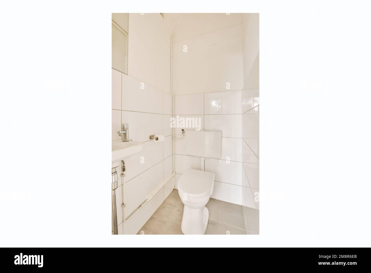 un piccolo bagno con piastrelle bianche sulla parete e servizi igienici in angolo, c'è uno specchio sopra di esso Foto Stock