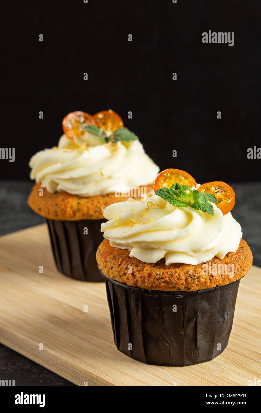 Cupcake con crema di formaggio decorato con frutti di bosco dolci su sfondo scuro. Layout per la progettazione Foto Stock
