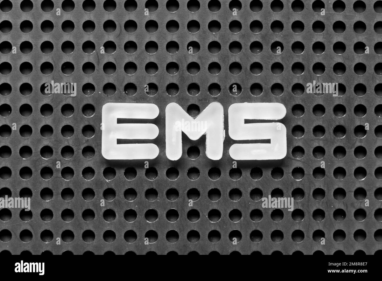 Lettera alfabetica bianca in parola EMS (abbreviazione di servizi medici di emergenza o servizio di posta espresso) su sfondo nero di pegboard Foto Stock
