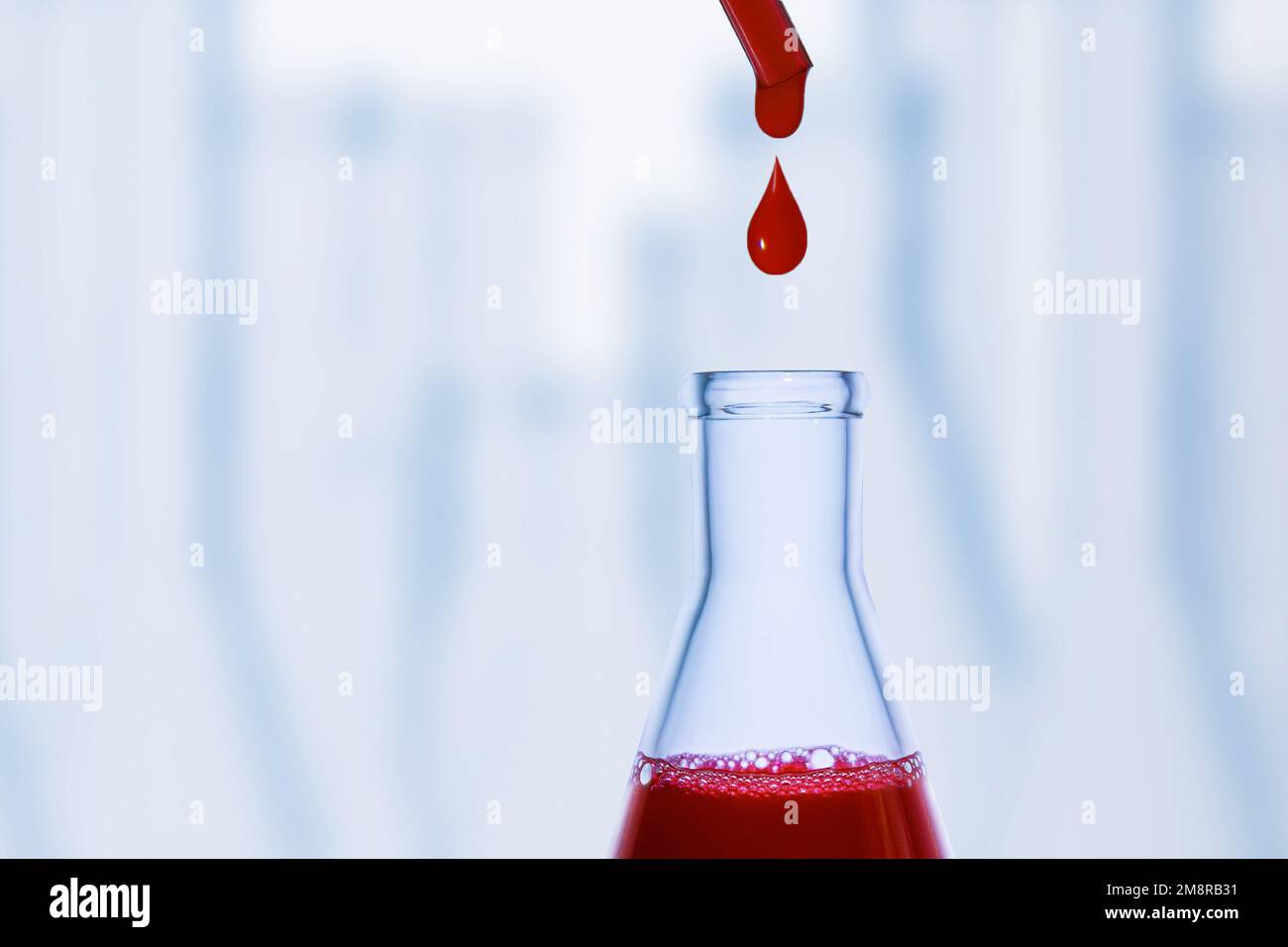 Una goccia di sangue. Pipetta. Pallone medico con liquido rosso. Matraccio con sangue. Gocciolamento di liquido rosso. Una goccia di rosso. Esami, gruppo sanguigno. Foto Stock