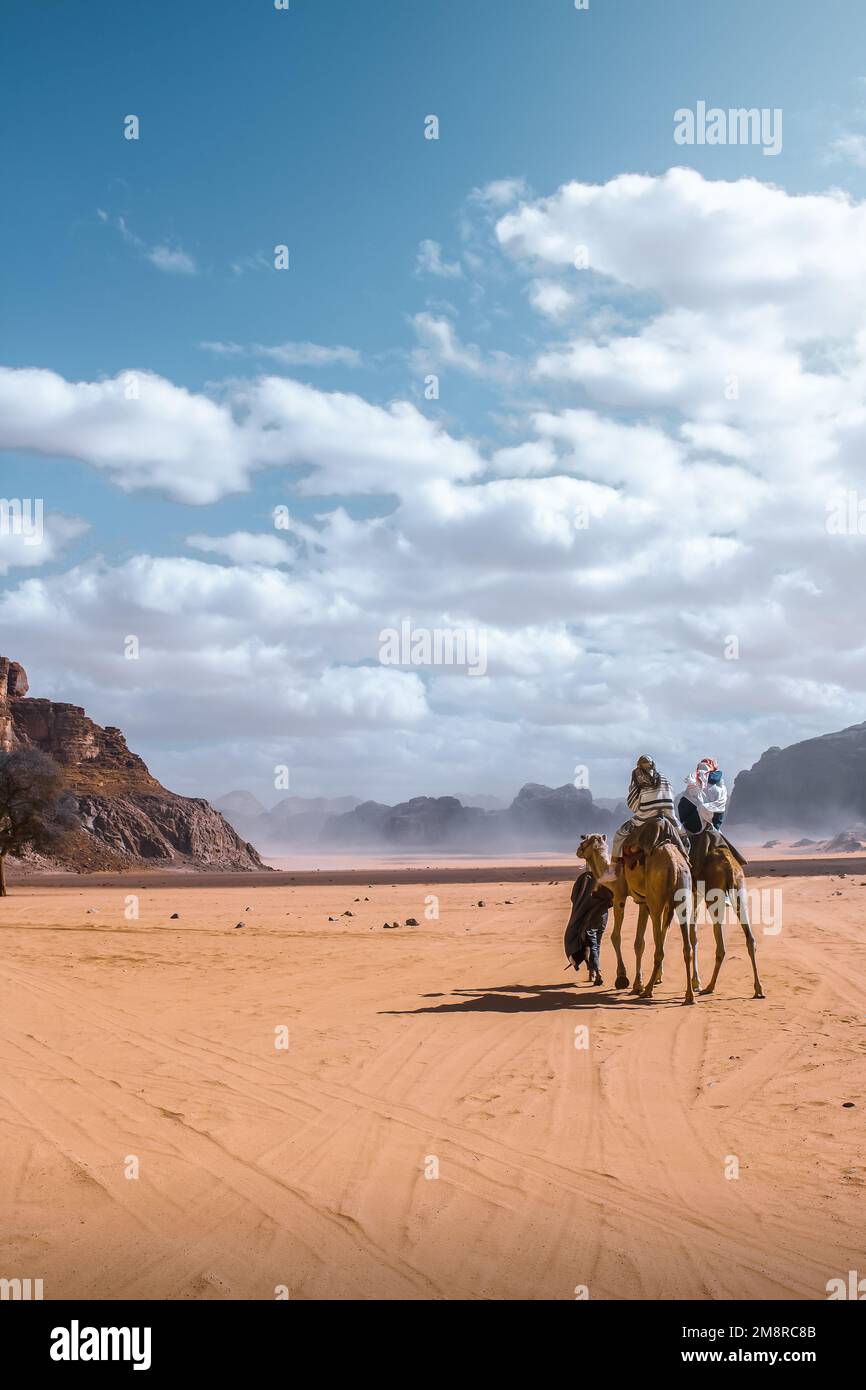 I turisti si godono un giro in cammello attraverso il deserto di Wadi Rum in Giordania, Medio Oriente. Foto Stock