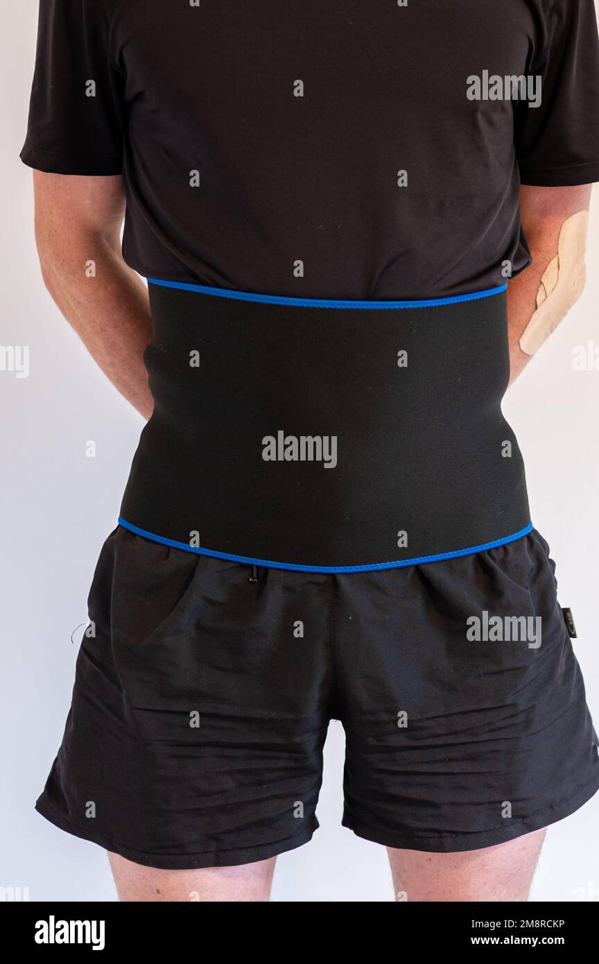 Un uomo con una cinghia di riscaldamento del supporto che usa per proteggere la spina dorsale o la perdita di peso Foto Stock