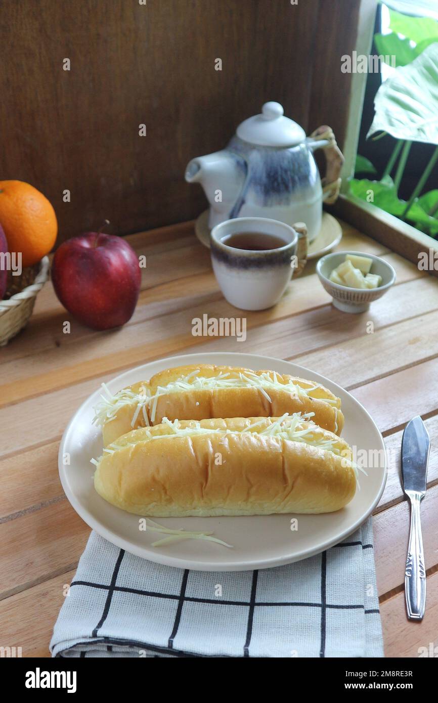 pane ripieno di formaggio servito su un piatto bianco con mele e una teiera sullo sfondo Foto Stock