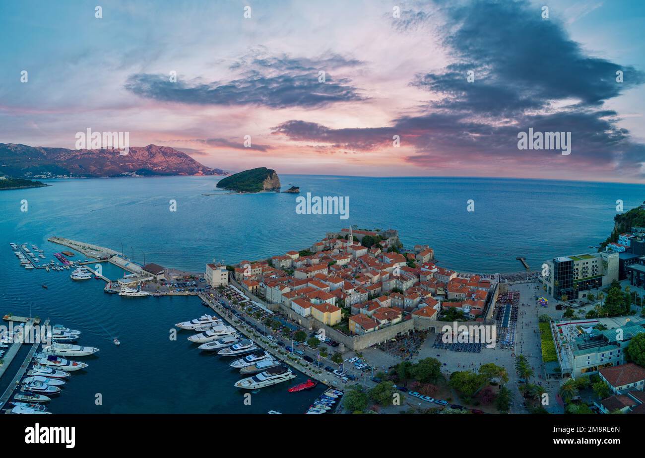 Panorama del porto marittimo con piccole navi e barche per escursioni sul mare Adriatico vicino all'antica isola storica di San Stevan al sole della sera Foto Stock