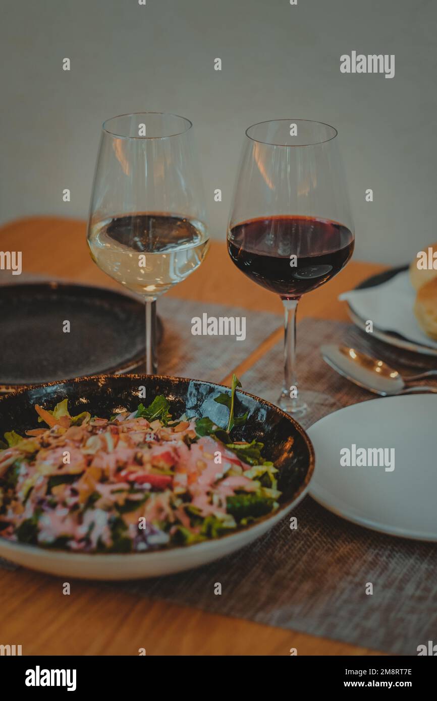 Tavolo da ristorante italiano con cena a base di insalata di pasta e un bicchiere di vino Foto Stock