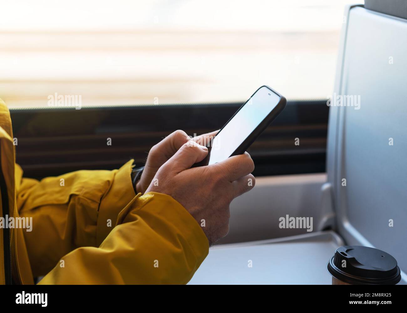 Uomo che utilizza lo smartphone mentre viaggia in treno cellulare in mani ravvicinate. Foto Stock