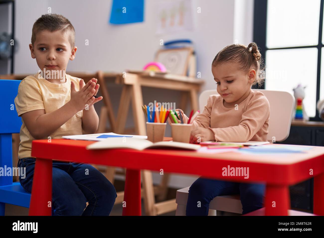 Due bambini studenti prescolare seduti sul tavolo disegno su carta presso l'asilo Foto Stock