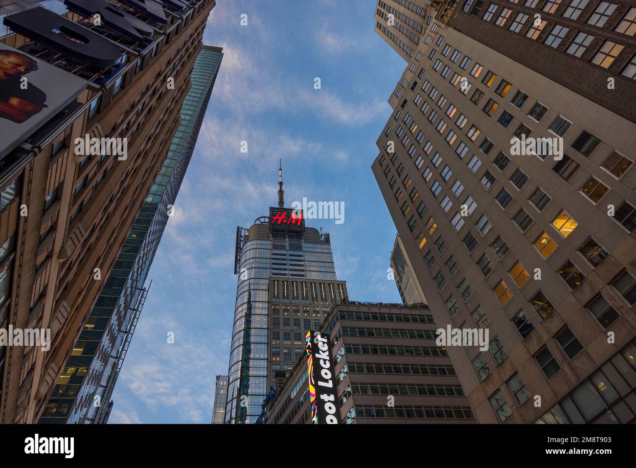 Splendida vista sui grattacieli di Manhattan e sui negozi H.M che pubblicizzano in cima alla torre contro il cielo blu con nuvole bianche. New York. STATI UNITI. Foto Stock