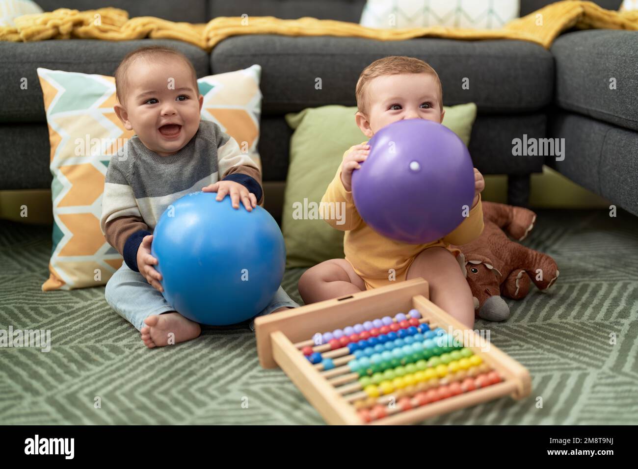 Due bimbi che giocano con palle e abaco seduti sul pavimento a casa Foto  stock - Alamy