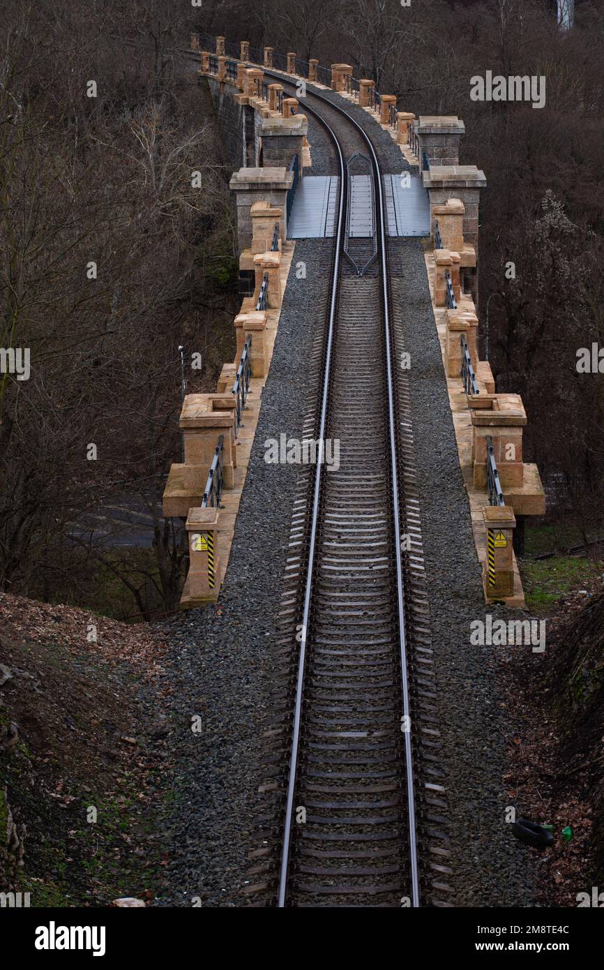 La ferrovia passa su un ponte di pietra e si gira. Foto Stock