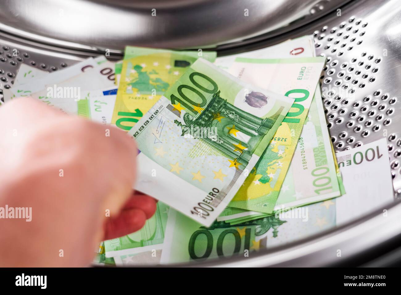 Euro cento banconote in lavatrice e in mano. Concetto finanziario di riciclaggio di denaro Foto Stock