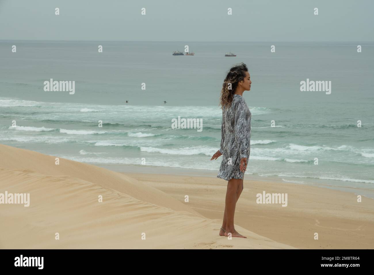 Donna vista in spiaggia con barche all'orizzonte Foto Stock