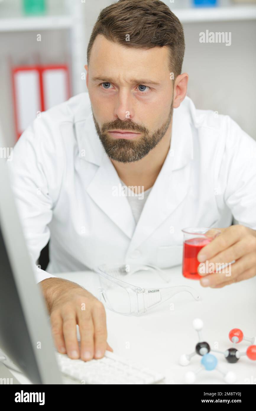 un assistente di laboratorio dell'uomo conduce gli esperimenti sul pc Foto Stock