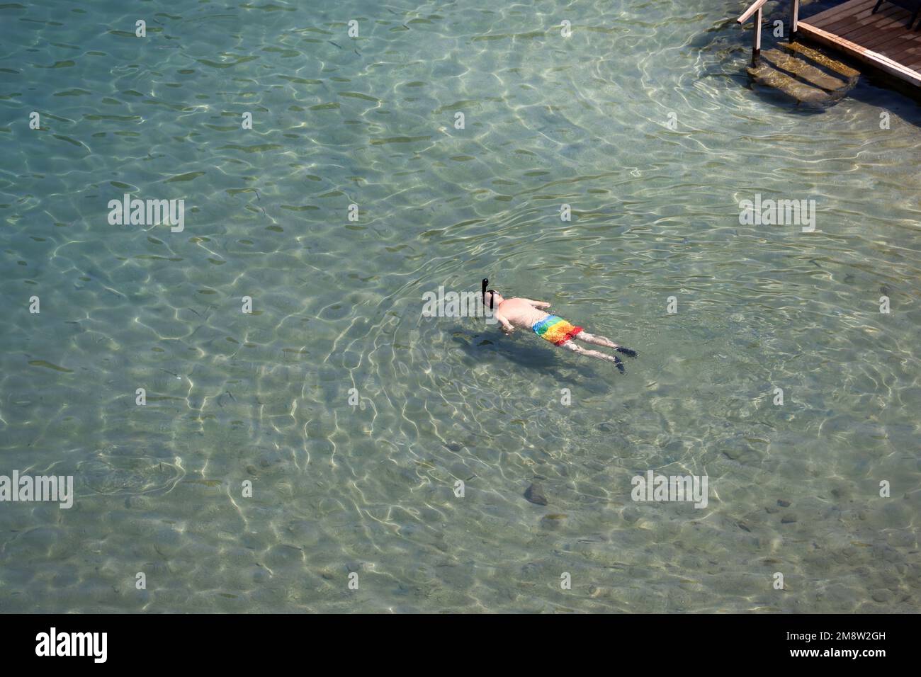 Vista aerea del mare e dell'uomo in maschera subacquea nuotare in acqua trasparente. Snorkeling e immersioni in una vacanza in spiaggia poco profonda Foto Stock