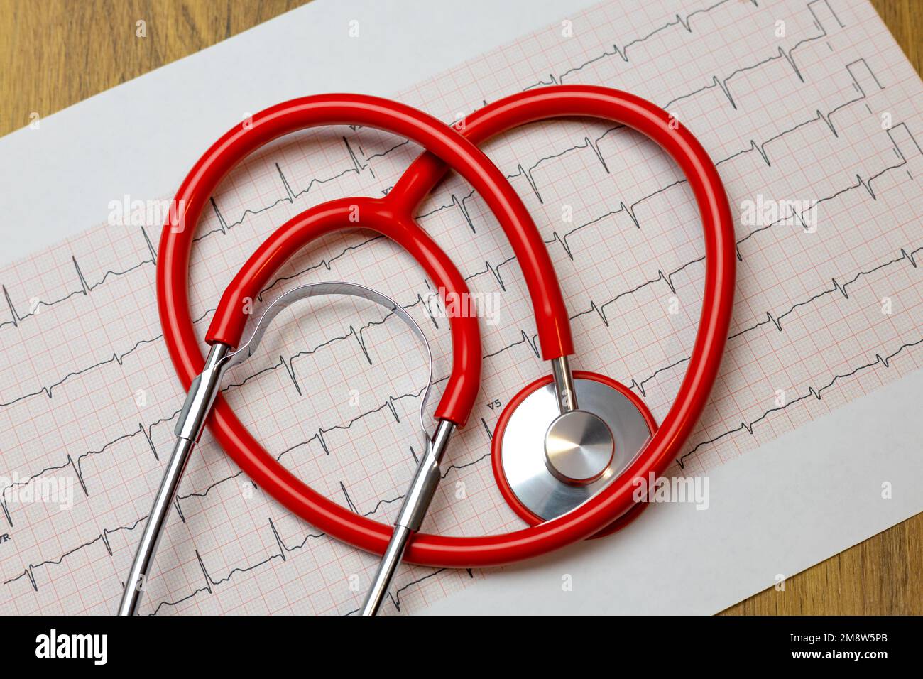 Primo piano dello stetoscopio a cuore rosso su carta per elettrocardiogramma (ECG) Foto Stock