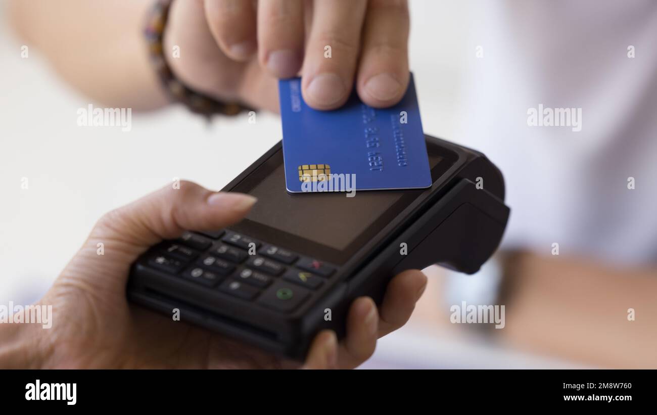 Mano maschile che tiene la carta di credito presso il terminale POS Foto Stock