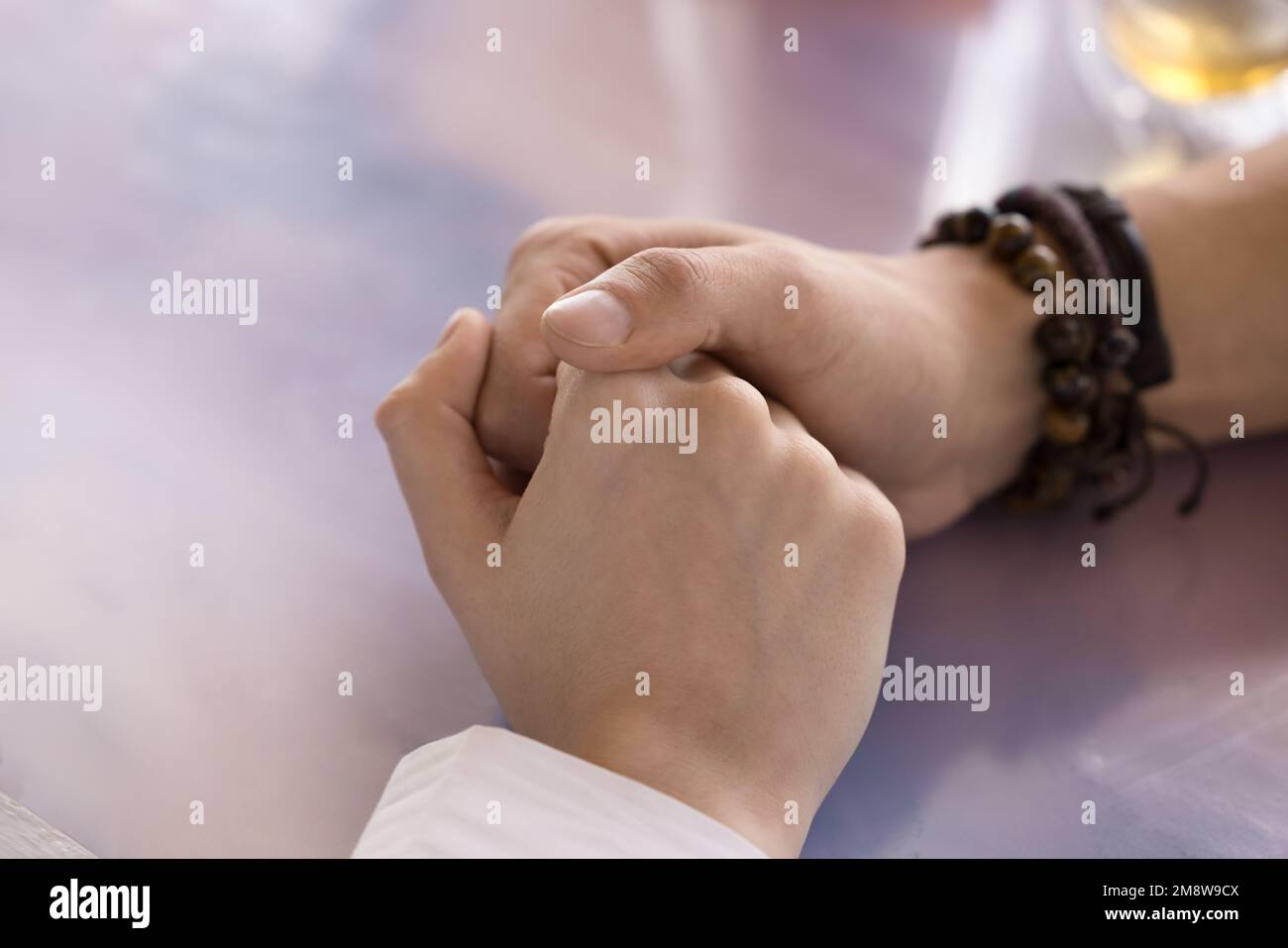 Giovane uomo che tiene le mani femminili sul tavolo, esprimendo l'amore Foto Stock