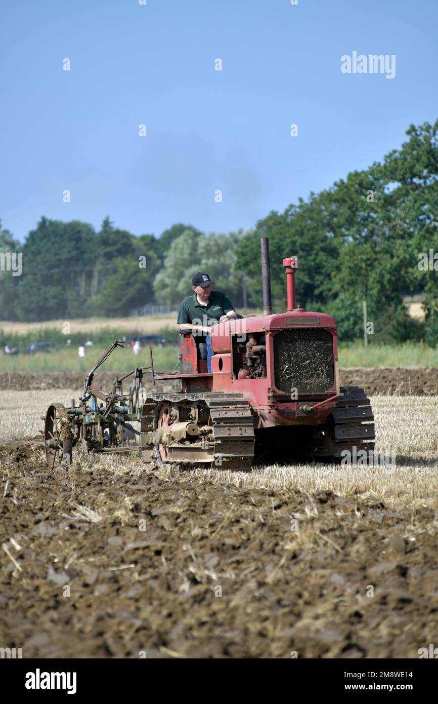 uomo che guida un trattore cingolato vintage che puliva un coltivatore vintage Foto Stock