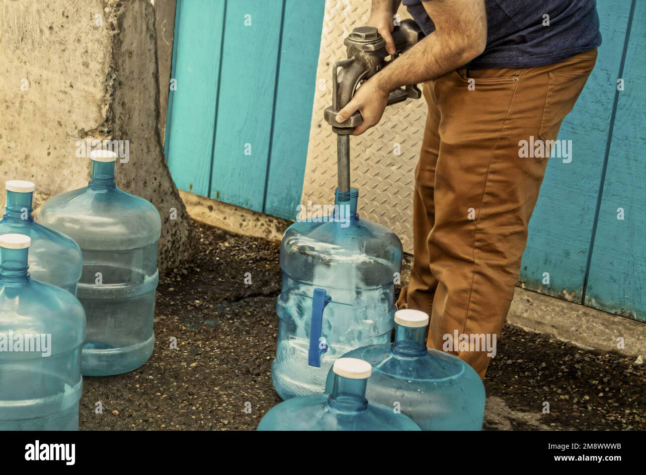 Giovane uomo che riempie cinque galloni caraffe per l'uso in cabina asciutta - senza acqua corrente - in Alaska USA Foto Stock