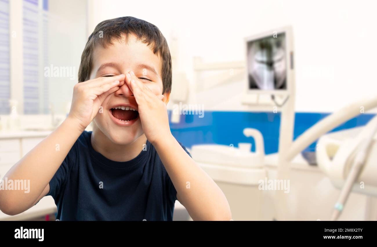 Bambino che indossa una t-shirt blu casual in piedi nella sala di consulenza. Gridando e urlando forte con mano sulla bocca. Concetto di comunicazione. Foto Stock