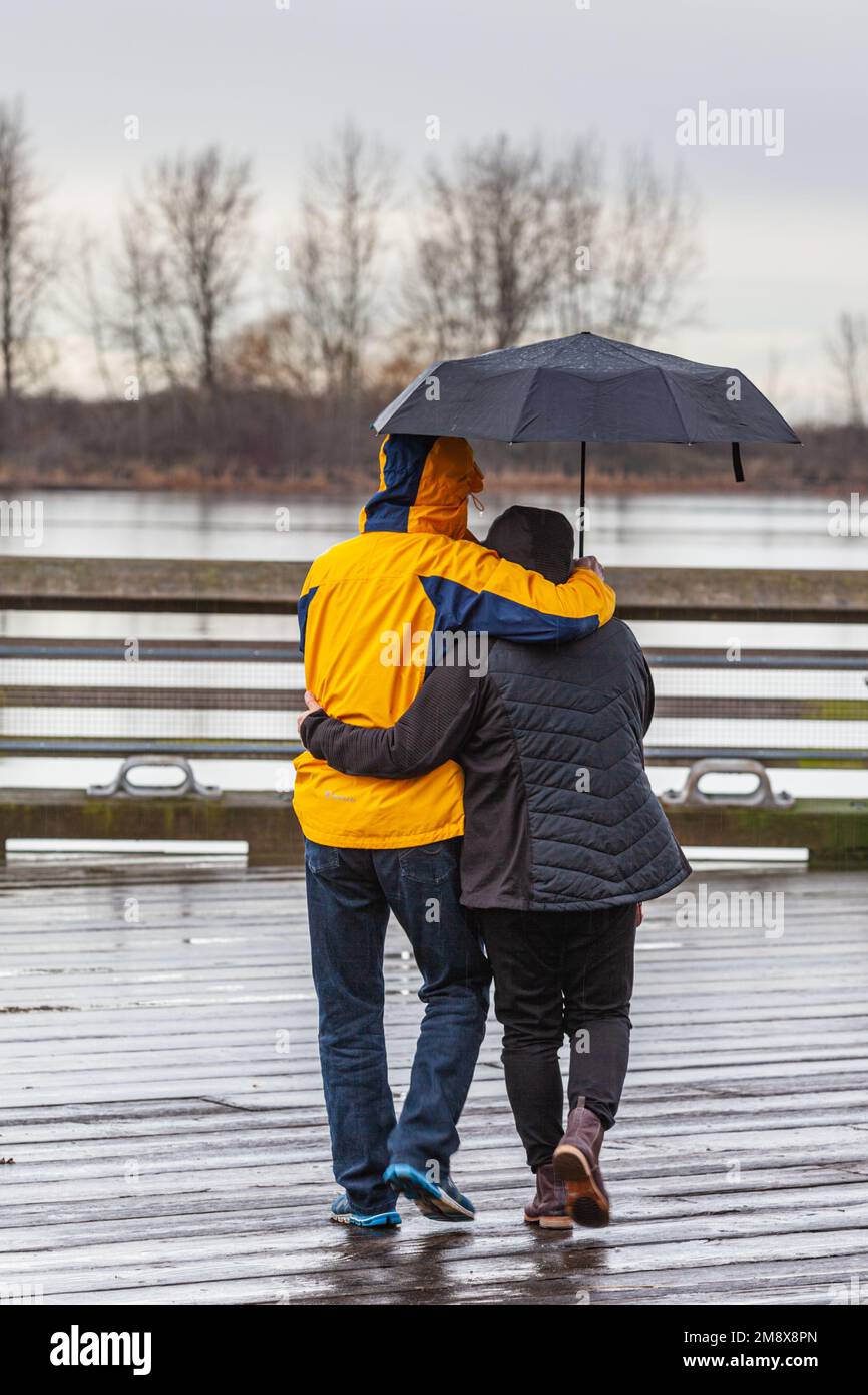 Coppia al riparo dalla pioggia sotto un ombrello in British Columbia Canada Foto Stock