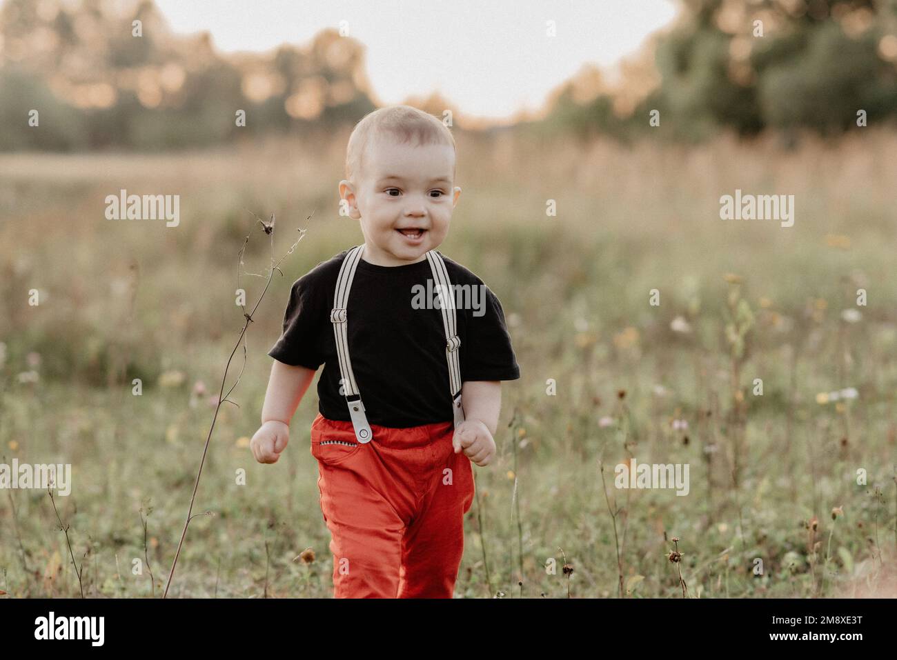 divertente bambino che corre sull'erba in campo estivo. La grana aggiunta simula la foto su pellicola Foto Stock