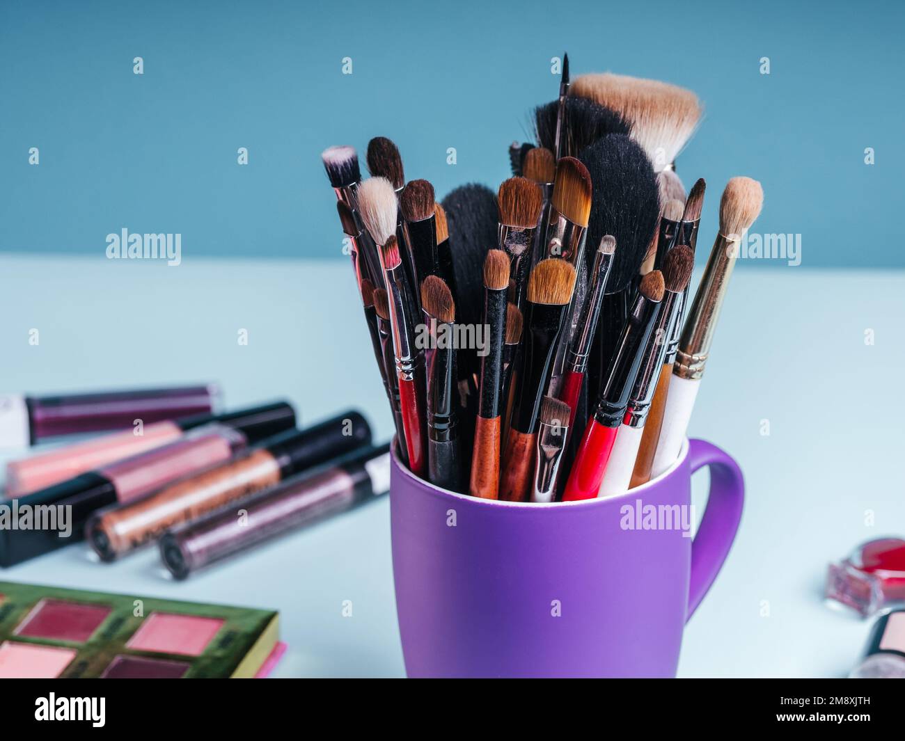 set di pennelli professionali per il trucco sullo sfondo di una tavolozza con ombre colorate e altri cosmetici per la bellezza delle donne Foto Stock