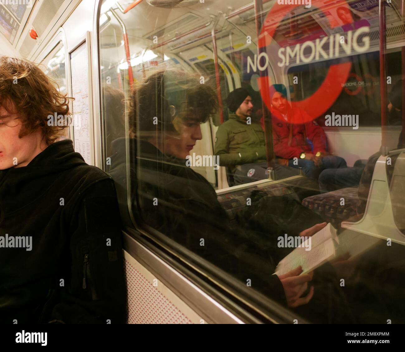I passeggeri della metropolitana di Londra, nota anche come la metropolitana, si riflettono nella finestra. Cartello per divieto di fumo e tubo. Londra, Inghilterra Foto Stock