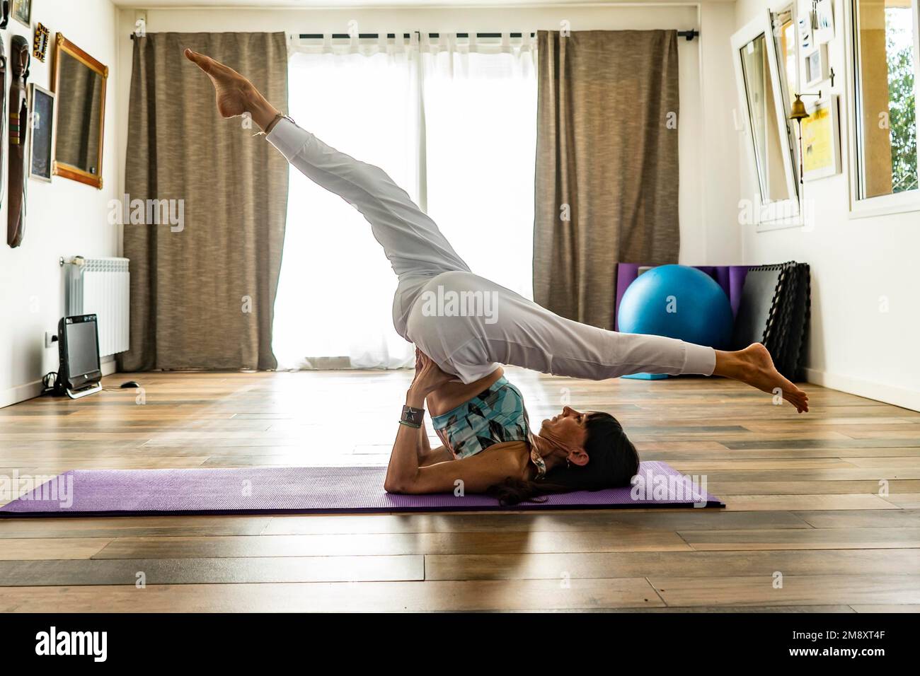 Vista laterale di una donna che pratica yoga su un tappetino. Studio Yoga Foto Stock