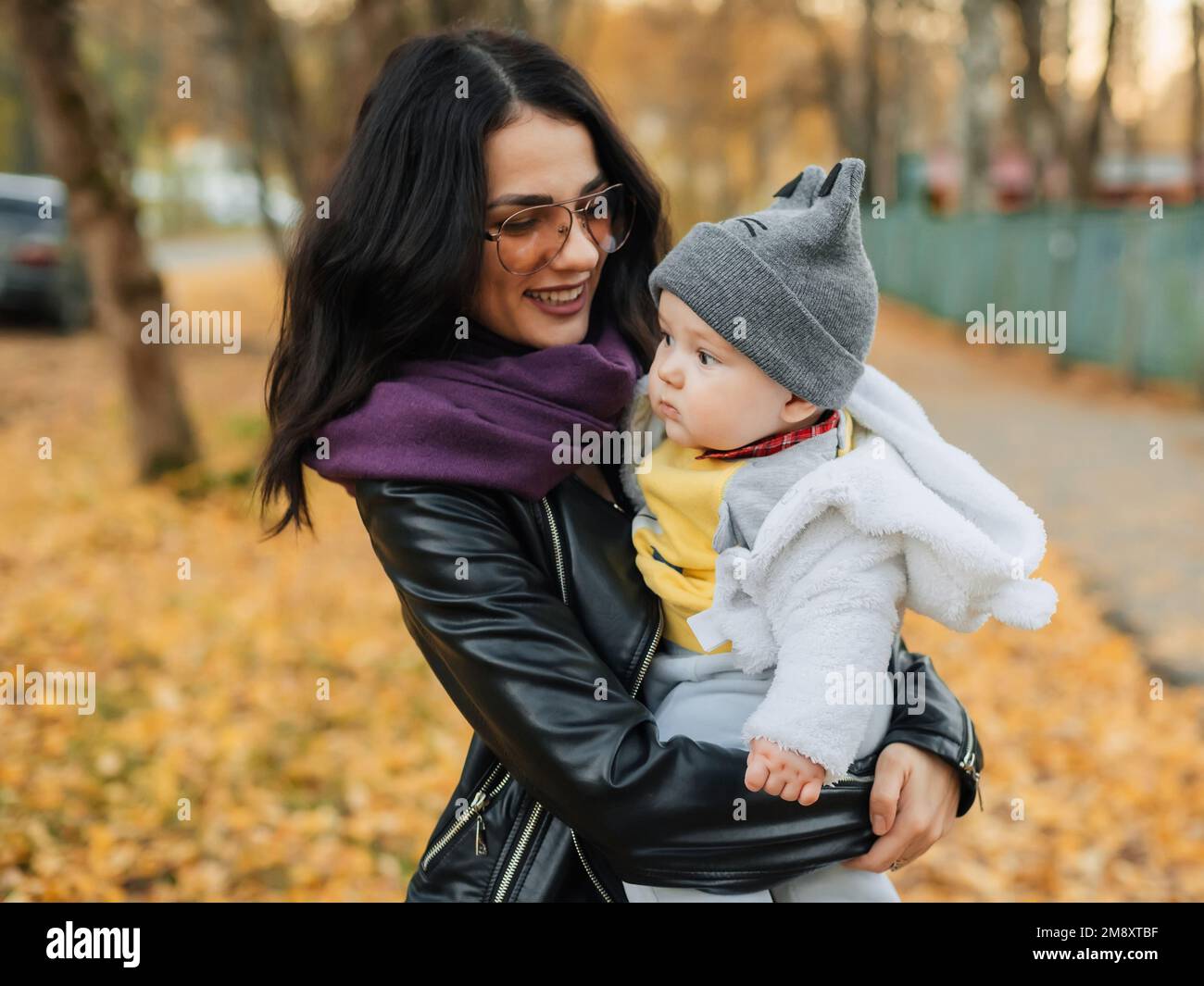 Giovane bella ragazza caucasica mamma sorridendo e tenendo il suo bambino bambino in autunno nel Parco Foto Stock