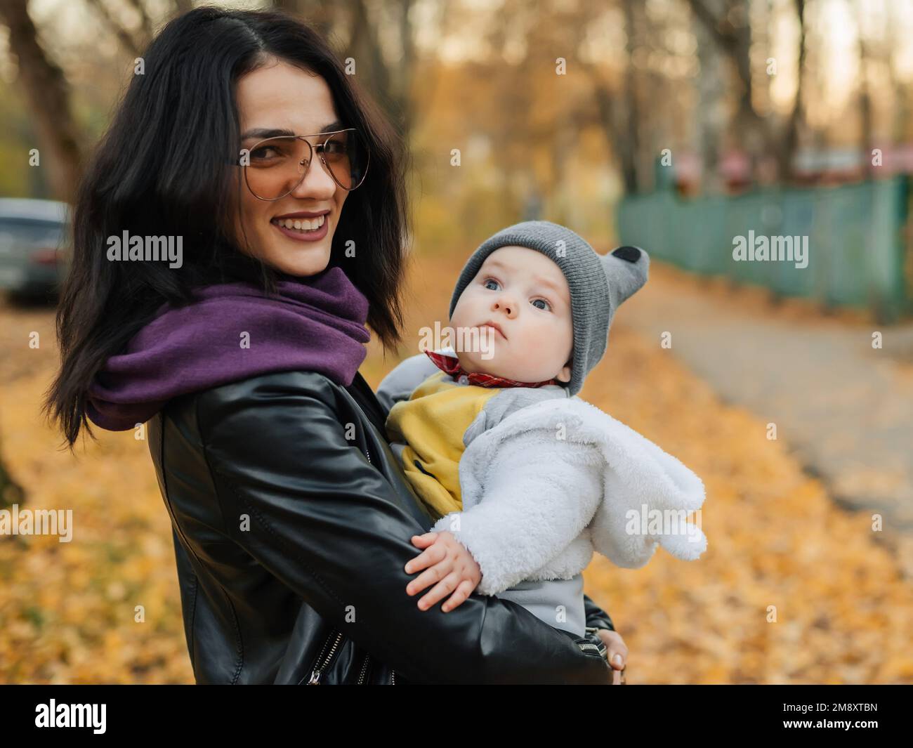 Giovane bella ragazza caucasica mamma sorridendo e tenendo il suo bambino bambino in autunno nel Parco Foto Stock