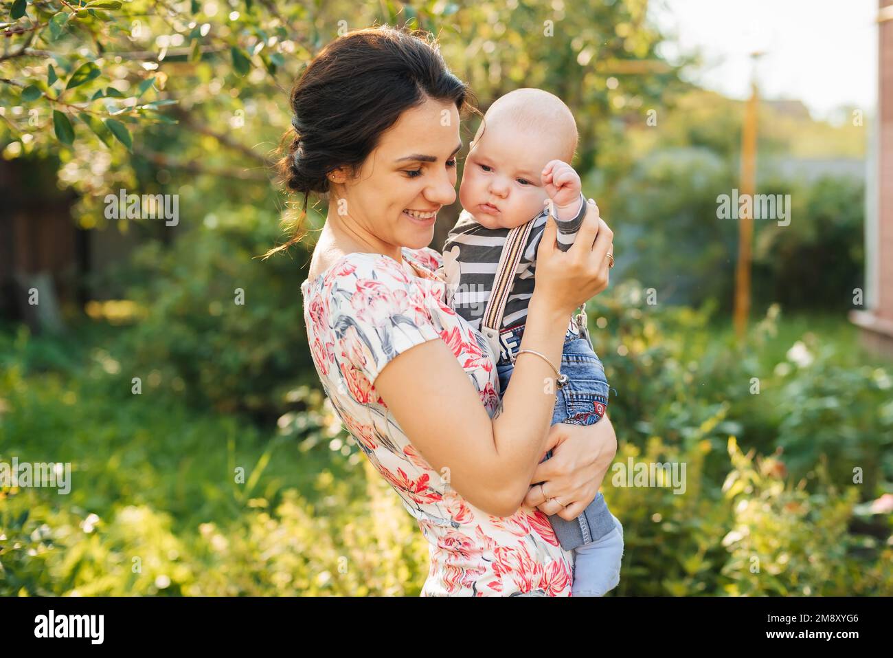 Felice giovane mamma caucasica con un bambino neonato in mano sorridente nel Parco in estate Foto Stock
