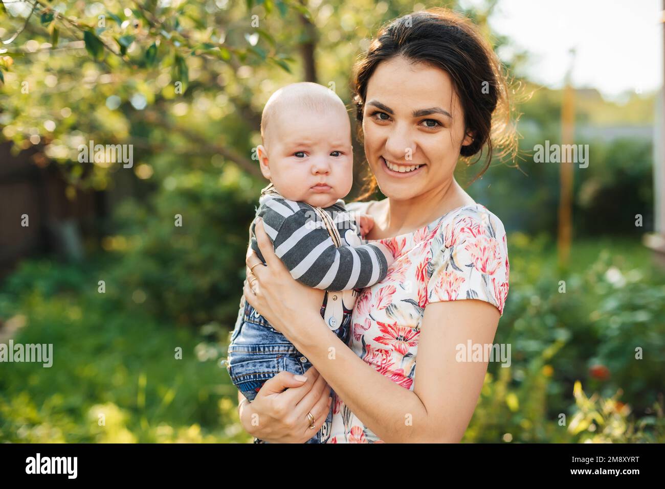 Felice giovane mamma caucasica con un bambino neonato in mano sorridente nel Parco in estate Foto Stock